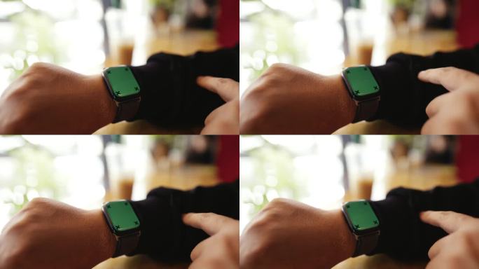 男子在咖啡店休息时触摸和滑动绿色屏幕的智能手表