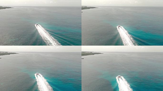 长长的白色尾迹快艇巡航在平静的海水沿着巴亚希贝海岸，拉罗马在多米尼加共和国。空中前进和复制空间