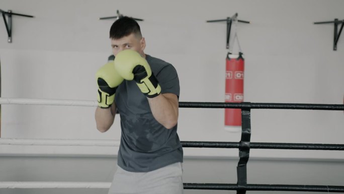 一个穿着运动服、戴着手套的职业拳击手在拳击场上展示拳脚的慢镜头