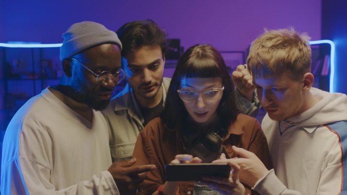 一群不同的年轻朋友在聚会上玩智能手机游戏