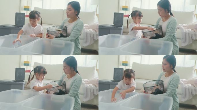 年轻的亚洲家庭妈妈教孩子如何回收帮助女孩意识到环境的重要性在家里的客厅。家庭幸福时刻。