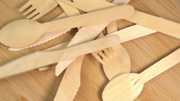 木质环保一次性餐具掉在桌子上。砧板上堆放着一堆木勺、刀叉。厨房、餐厅一次性生态餐具
