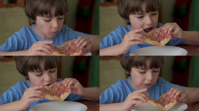 饥饿的孩子咬了一口披萨。吃披萨。饥饿的小男孩坐在家里厨房的餐桌上吃着美味的意大利披萨。不健康的营养快