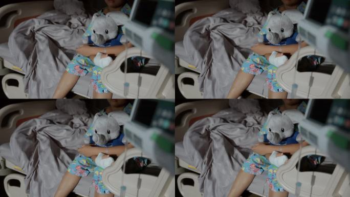 一个生病的小男孩坐在医院的病床上，抱着一个柔软的玩具——大象娃娃，昏昏欲睡地躺在病房里