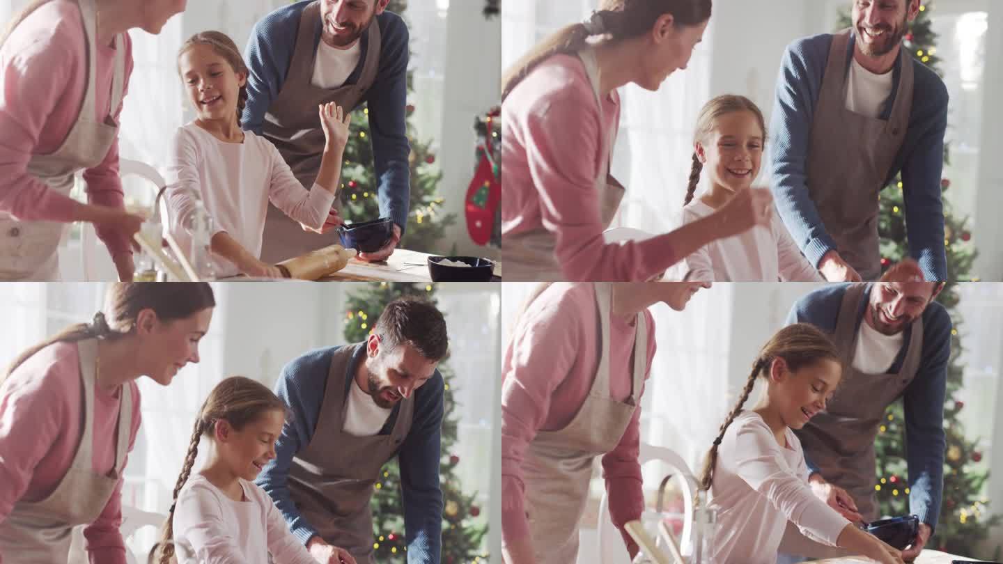 圣诞节快乐的家庭:可爱的小女孩学习如何制作饼干，并与父母一起庆祝她的成就的慢动作肖像。可爱的一家人一