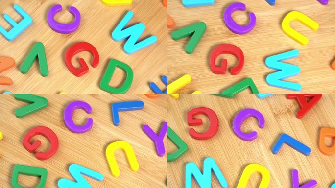 彩色字母在木制背景上旋转。学习的概念，学校或大学和知识。塑料英文字母，拉丁文