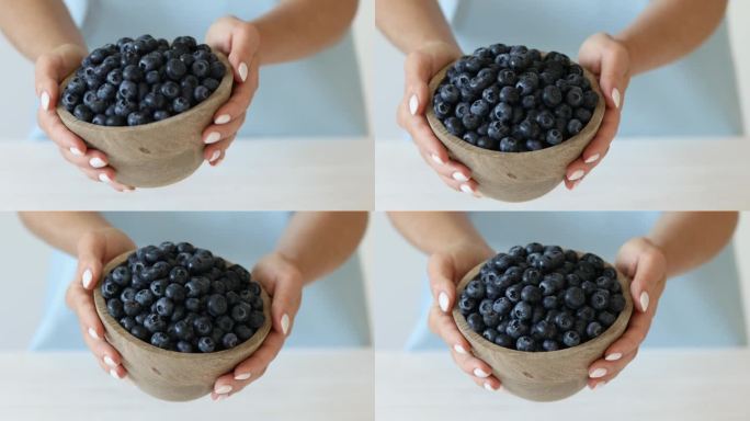 蓝莓在碗里。女人的手捧着一碗成熟的浆果。