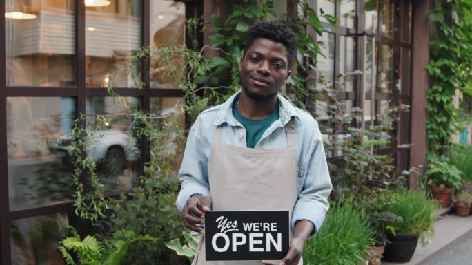 非裔美籍男性咖啡馆员工举着信息招牌