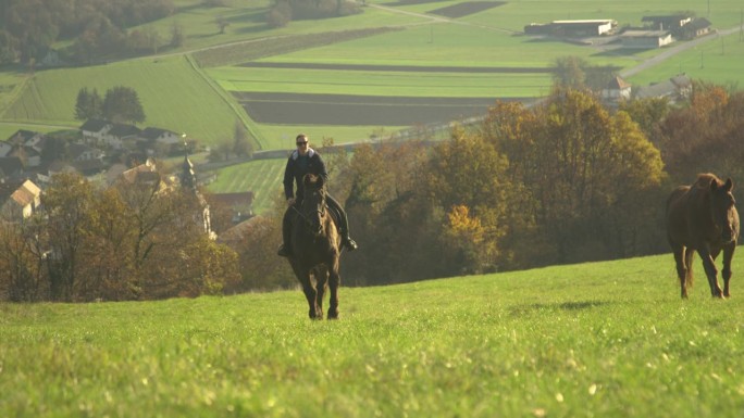 慢镜头:欢快的女人骑着马在草地上俯瞰山谷