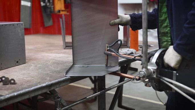 工厂里的工人正在点焊金属零件。他正在使用专门的现代化设备进行点焊