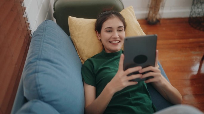 连接幸福:不同的年轻女性微笑着在家里舒适的沙发上享受科技。