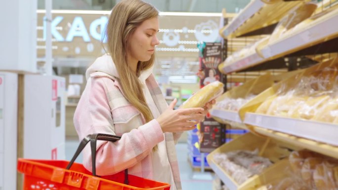 金发女郎在超市买新鲜的小麦面包，闻着面包的香味。