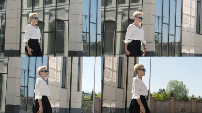 自信有型的成熟女人走在城市的街道上，穿着时髦的衣服别致的白衬衫和黑色流苏裙，戴着太阳镜，时尚的风格标