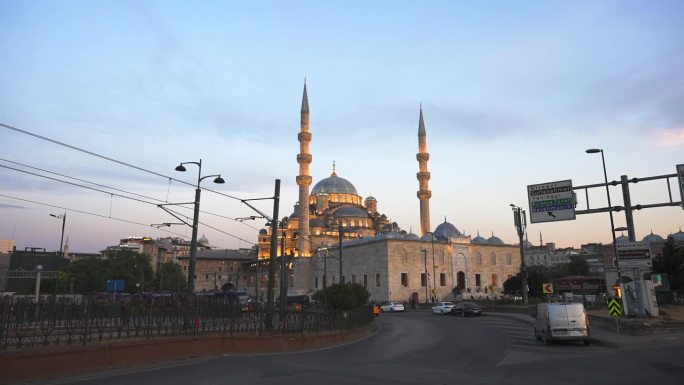 夕阳下的新瓦利德苏丹清真寺。汽车和出租车从加拉塔大桥驶出。土耳其伊斯坦布尔