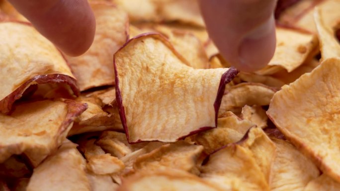 一只手从一堆干烤苹果片中拿起一块