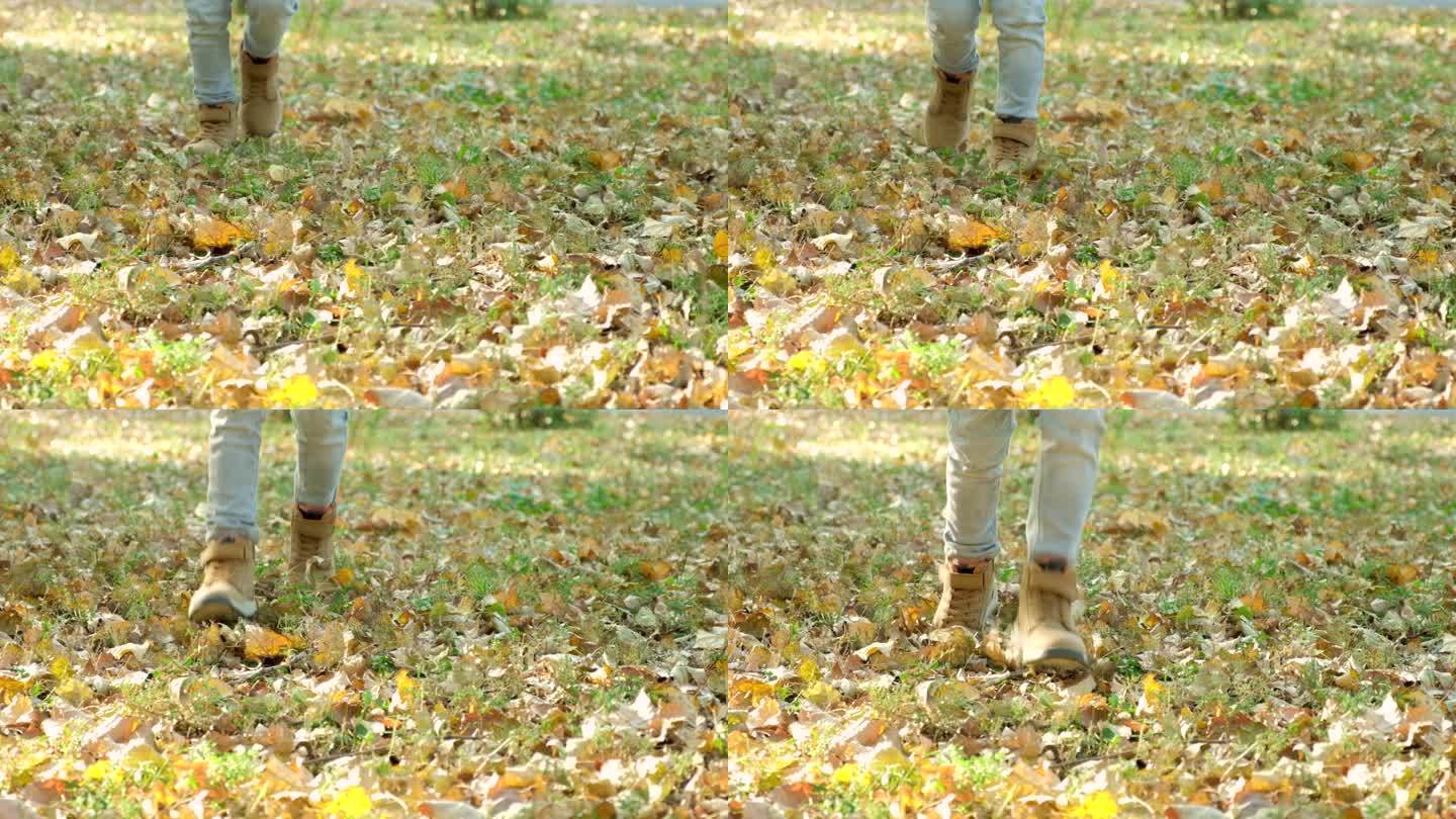 一个小孩子穿着舒适的童鞋在秋林的树叶上奔跑，双脚特写慢动作