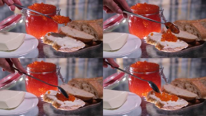 一个女孩在透明的桌子上用红鱼子酱做三明治，鱼鱼子酱是财富的奢侈品。黑底面包片