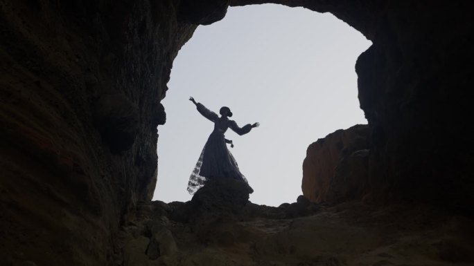 一个女人在悬崖边举起双臂
