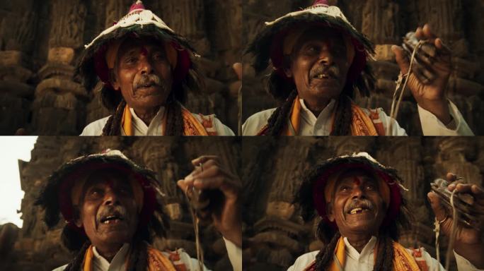 一位身着传统服装的印度老人在古老的印度寺庙里演奏乐器和诵经的特写肖像。老爷子用宗教音乐弘扬丰富的文化