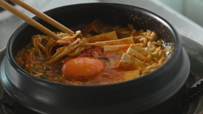 韩式辣面汤，以泡菜、豆腐、鸡蛋和蘑菇在韩式石碗中烹饪，用筷子吃