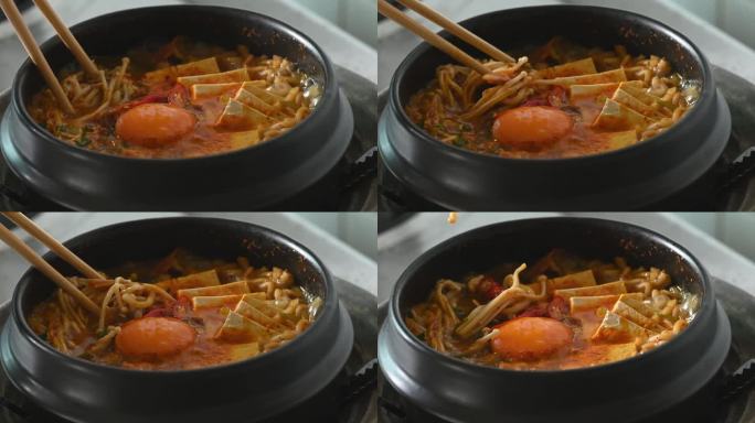 韩式辣面汤，以泡菜、豆腐、鸡蛋和蘑菇在韩式石碗中烹饪，用筷子吃