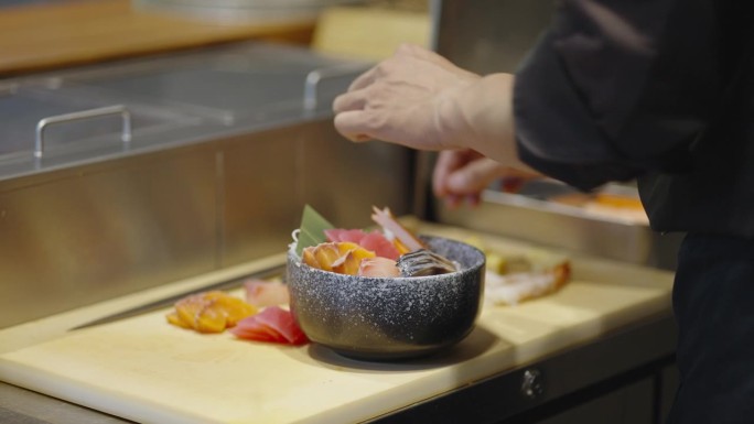 在居酒屋餐厅，寿司师傅将切成薄片的生鱼和海鲜放在醋饭上，准备做清蒸东武饭，并为客人提供服务。