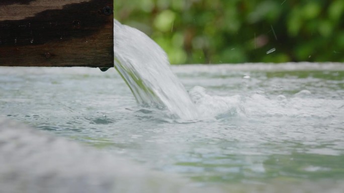 水从管道流出，雨滴落入水中