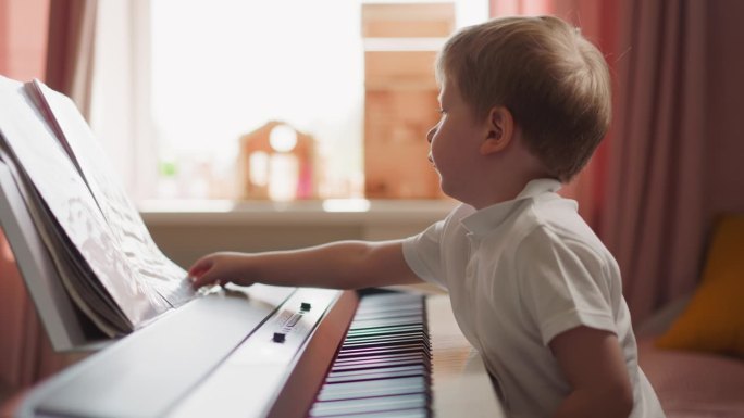聪明的男孩坐在电子钢琴前翻乐谱