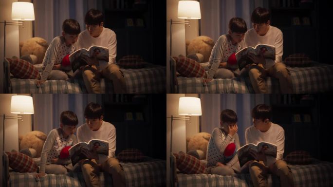 韩国父亲在睡觉前给他可爱的儿子读童话故事。耐心的父亲帮助儿子学习如何阅读他最喜欢的书。亲子亲密时刻