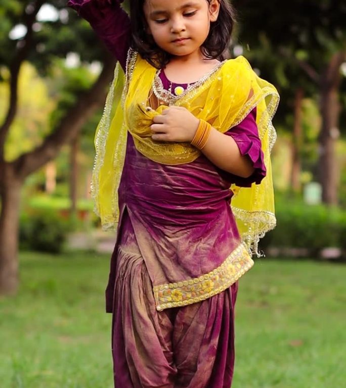 身着传统服饰的女婴在公园里玩土