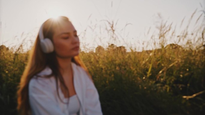 日落时分，女子在草地上欣赏音乐