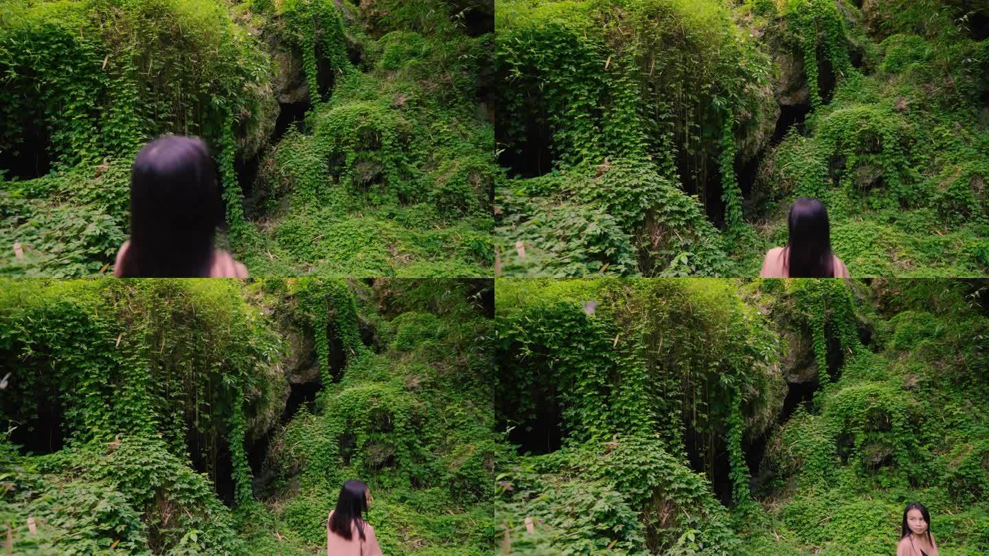亚洲女子在茂密的绿色神奇梦幻森林里看着蝴蝶