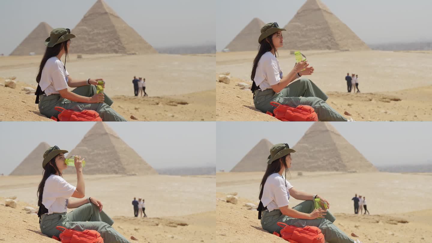 埃及，开罗，亚洲女游客坐在岩石上，背景是吉萨大金字塔