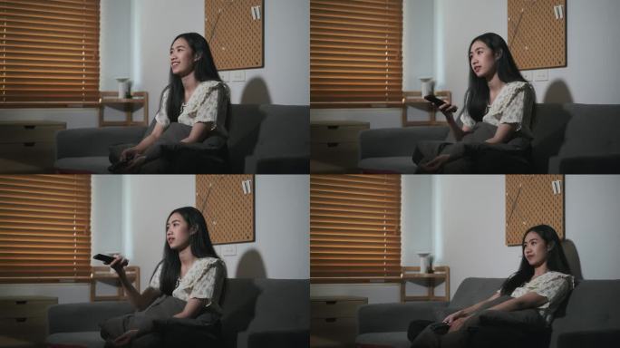 年轻的亚洲女人拿着遥控器切换频道，晚上在家看电影。