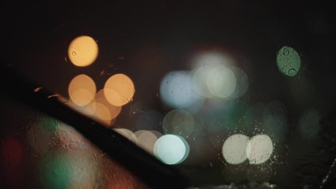 晚上在雨中开车。汽车玻璃雨刮器夜景