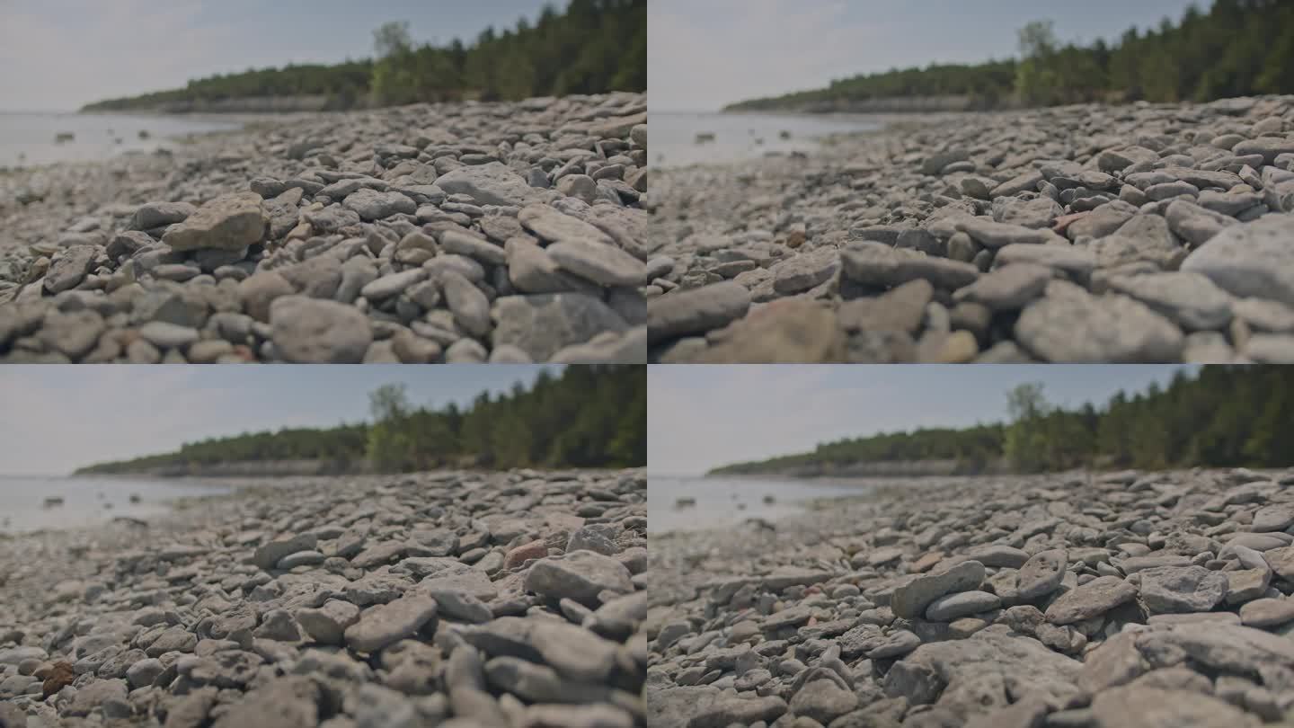 卵石滩。在阳光明媚的日子里，低角度平滑的相机运动在浅灰色的鹅卵石上。在爱沙尼亚的北欧海岸线拍摄。环境