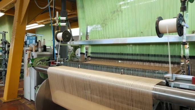 织布机。纺织厂设备。纺织厂正在工作的工业织布机。编织。