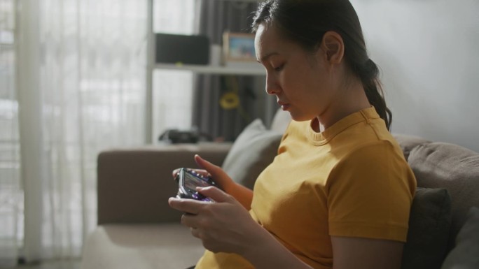 亚洲女性在家玩掌上游戏机
