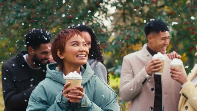 一群朋友穿着大衣站在外面，拿着外卖的热巧克力饮料