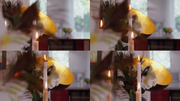 缓慢暴露的蜡烛在被植物包围的餐具柜上燃烧的镜头