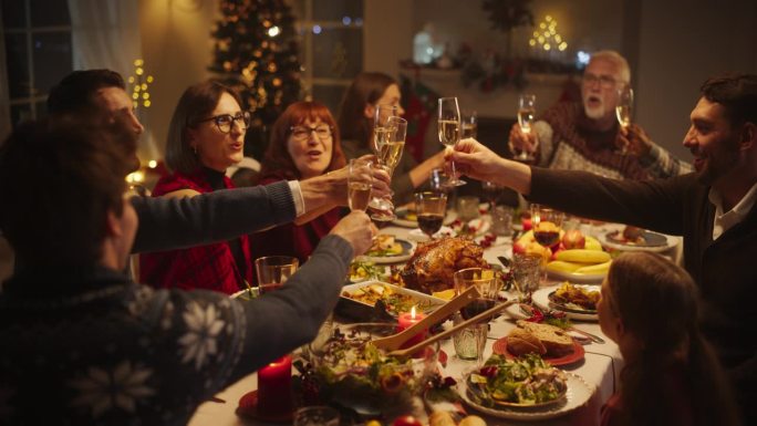 父母，孩子和朋友在一个舒适的家一起享受圣诞晚餐。亲戚们一起吃饭，举杯共饮香槟，敬酒，庆祝寒假