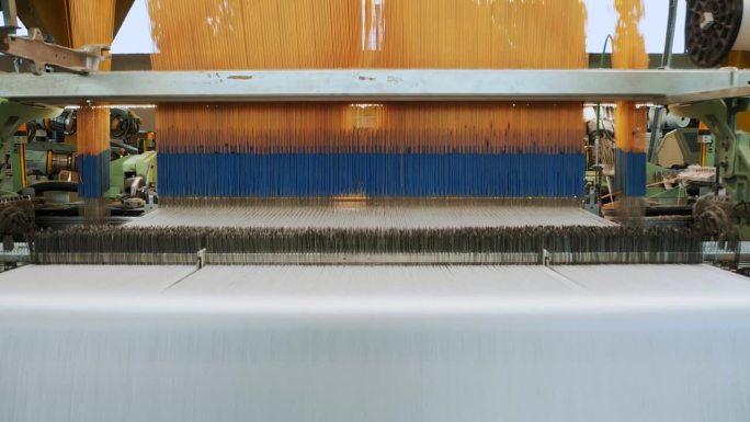 织布机。自动织布机正在织造线布。纺织工厂。纺织工业。纺织厂设备。面料生产。