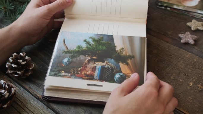 一个人拿着家庭相册翻看圣诞照片。