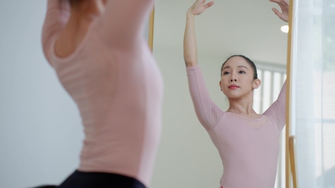 身着粉黑色芭蕾舞裙的美丽女芭蕾舞演员在芭蕾舞工作室排练，成年女芭蕾舞演员上台前的训练，优雅的女芭蕾舞