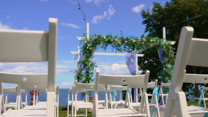 婚礼装饰沙滩设置海滨花拱与座位舞台，为婚礼司仪