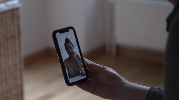 女性通过智能手机聊天的视频交流场景。近距离手持手机设备与远方的朋友交谈