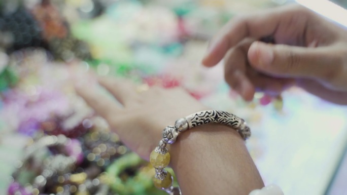 亚洲妇女在饰品店选购手工制作的手链或手镯。
