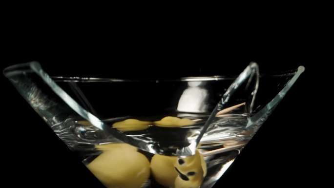在破碎的马提尼鸡尾酒杯里，一根牙签上的橄榄在慢镜头中掉落。