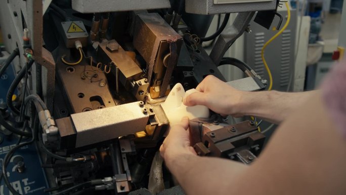 在制鞋厂的一台特殊机器上手工制鞋的特写镜头。男工人在一台专门生产鞋子的机器上工作