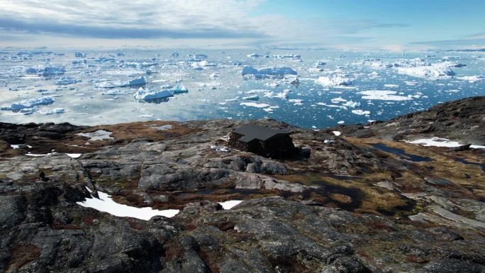 位于格陵兰岛岩石海岸的偏远科学家站，背景是冰山，鸟瞰图